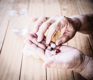 Foto: Eine ältere Person hält Tabletten in der Hand.